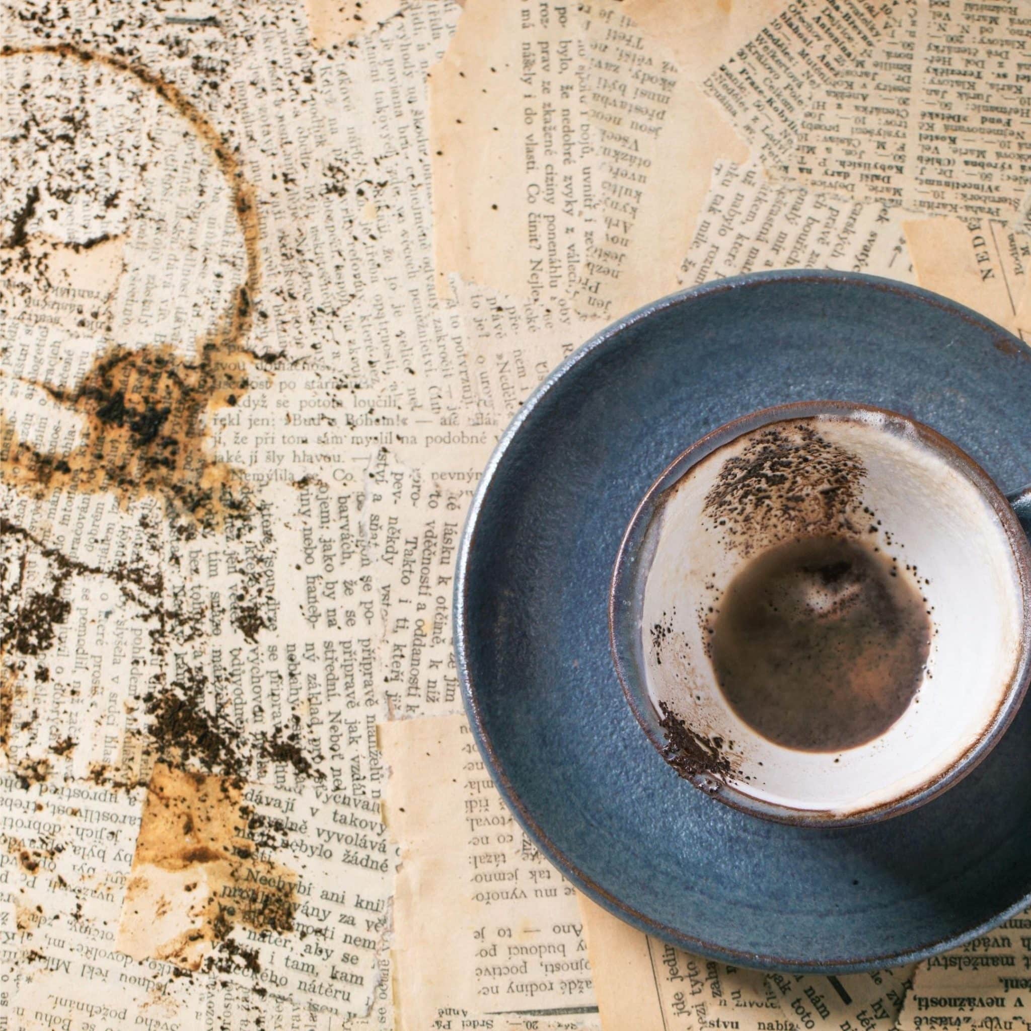 Tasse vide avec des traces de marc de café sur fond de vieux journaux, utilisée pour une lecture de cafédomancie