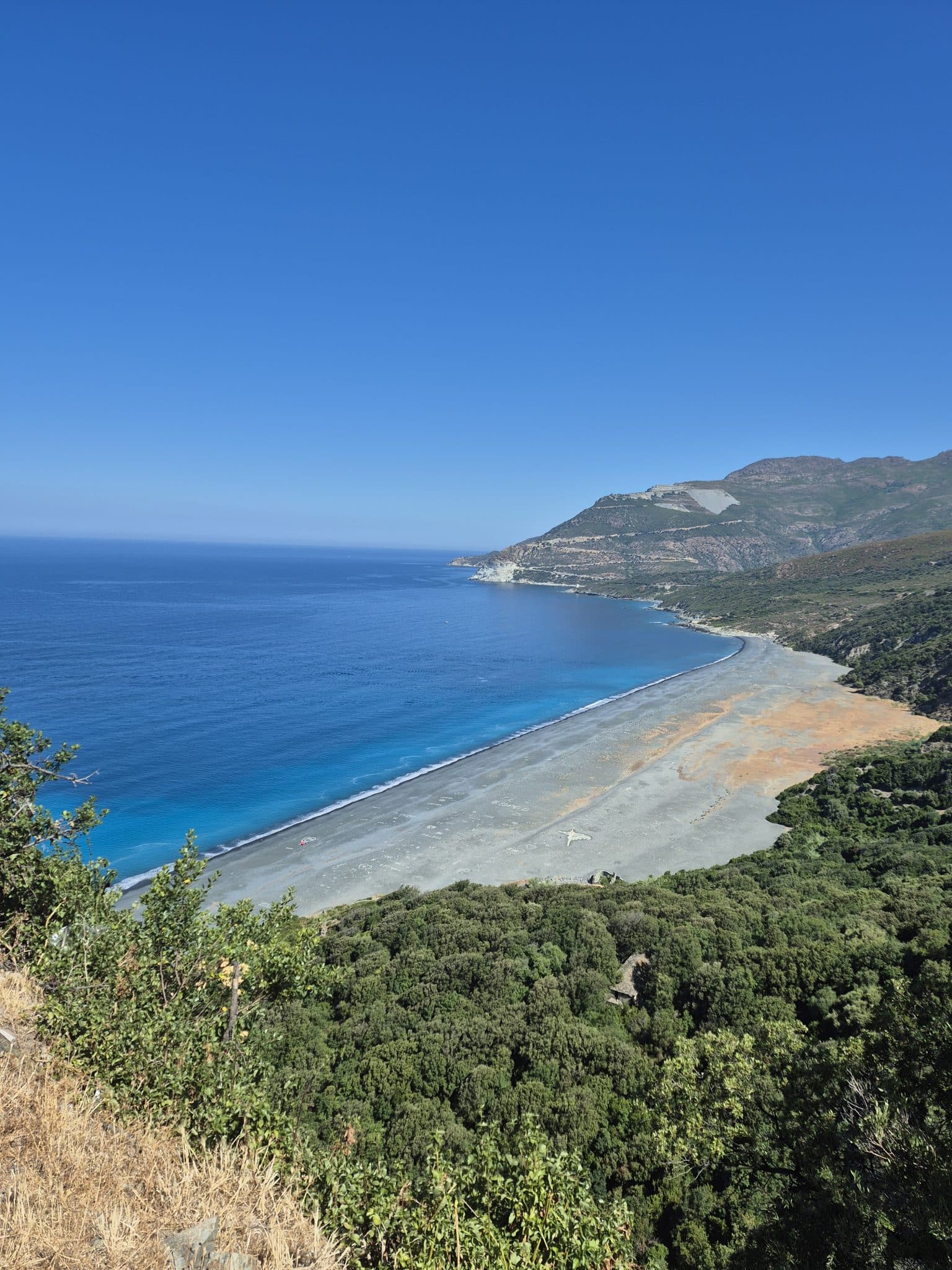 Vue panoramique sur la plage de sable noir de Nonza en Haute-Corse, avec la mer Méditerranée en arrière-plan, prise lors d’une excursion avec Kurnos Évasion depuis Bastia