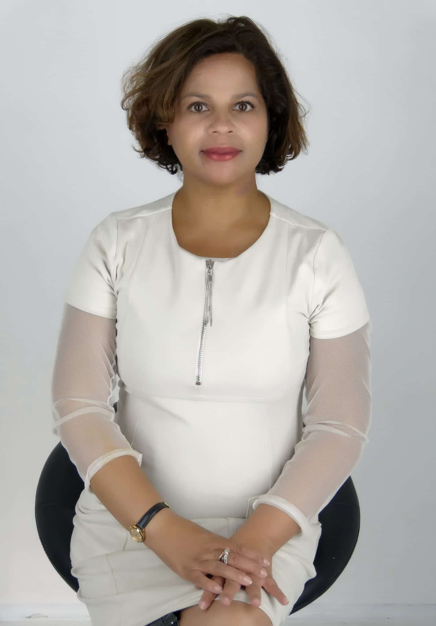 Soraya Dulorme, célèbre médium, en robe blanche, posant assise pour un portrait professionnel