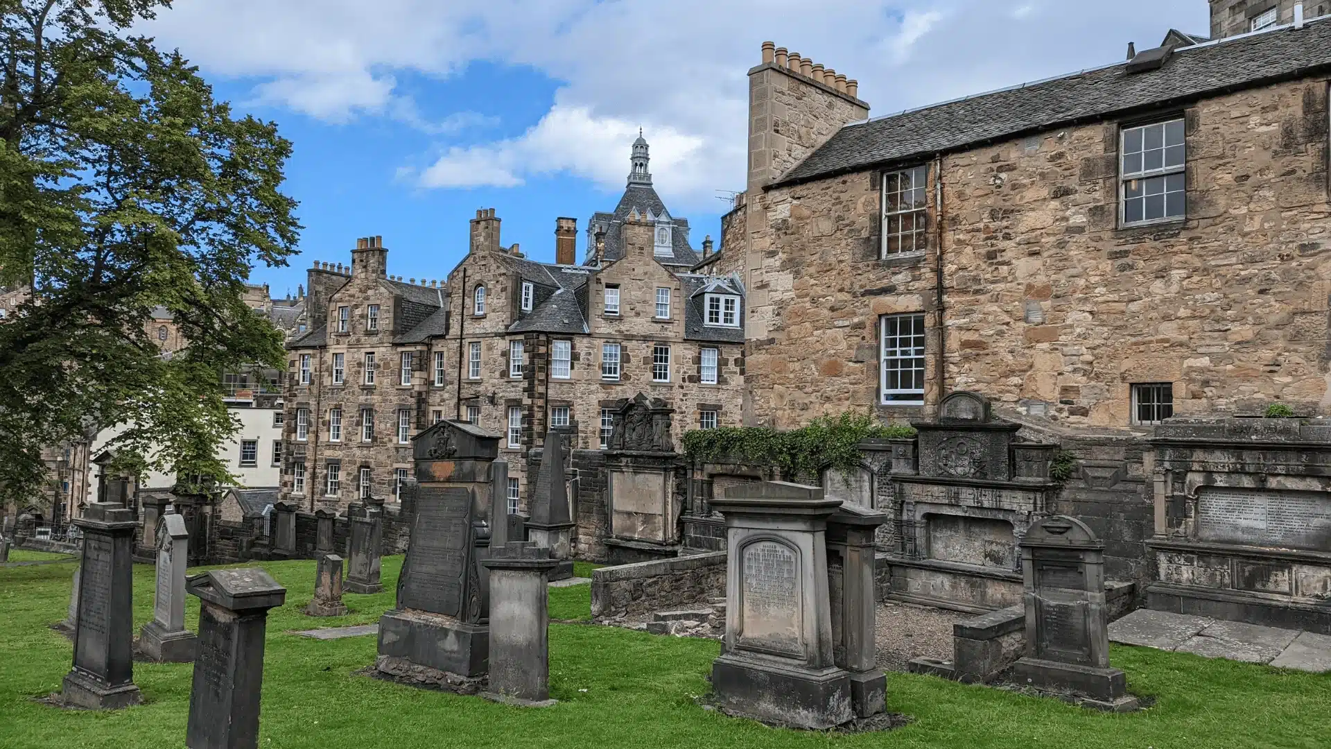 Vue du cimetière Greyfriars Kirkyard à Édimbourg, entouré d’anciennes pierres tombales et de bâtiments historiques, connu comme le cimetière le plus hanté du monde.